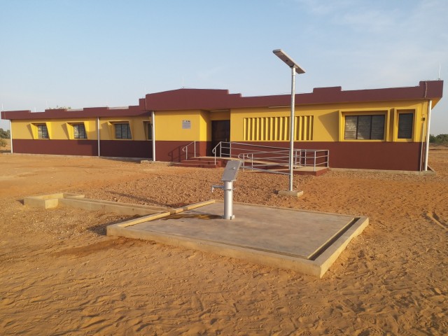 A recently completed health clinic, with a water well hand pump on a concrete pad and a solar powered light pole seen in the foreground, is seen here in the remote village of Money in Benin in Africa. The clinic and various associated facilities also built comprise one of two similar clinic projects recently completed by the U.S. Army Corps of Engineers in that region of Benin through funding from AFRICOM and coordinated closely with the U.S. State Department. (Photo courtesy of Cosme Quenum)