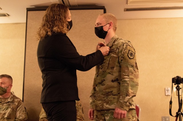 Heather McBain, mother of Spc. Justice McBain, pins the Soldier’s Medal onto her son’s left collar during the Soldier’s Medal presentation ceremony, April 11, 2021, at Milwaukee, Wisconsin. (U.S. Army Reserve photo by Maj. Jeku Arce)