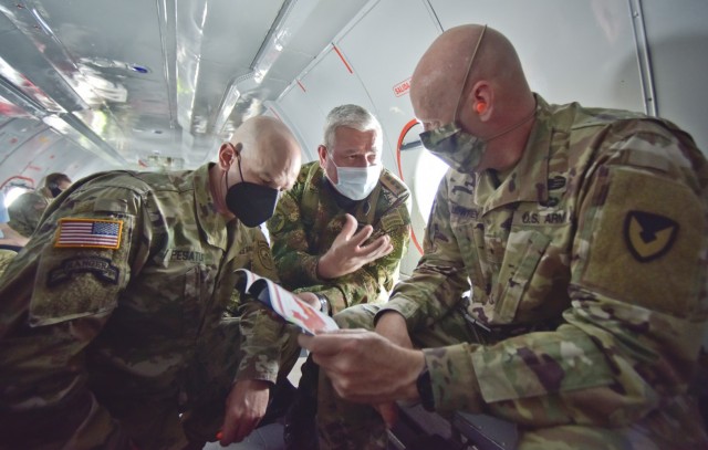 Maj. Gen.Elder Giraldo, chief of operations for the Columbian Army, center, briefs Brig. Gen. Douglas Lowrey, commander of U.S. Army Security Assistance Command, during a quick huddle inside a Colombian aircraft flying over Colombia, 5 April 2021. Lt. Col. Andrew Pesature, left, Army Chief of Missions at U.S. Embassy, provides translation services. Lowrey and members of his staff visited several sites to see the impact of U.S. security assistance and foreign military sales, in support of the Colombian military in defending their country from counter-narcotic and internal terrorist threats. (U.S. Army photo by Richard Bumgardner)