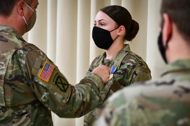 Cpl. Brittney Lozoya-Salazar receives a medal and certificate from Col. Bryan Love, 207th Military Intelligence Brigade commander, during an award ceremony at Caserma Ederle, U.S. Army Garrison Italy in Vicenza, on Sept. 18, 2020. Under a new Army directive, all active duty and Active Guard Reserve Soldiers  who have been recommended for promotion to sergeant and have graduated from the Basic Leader Course will be laterally promoted to corporal beginning July 1. Soldiers who are currently corporals must meet both requirements in order to keep their rank or they will be designated as specialists. 