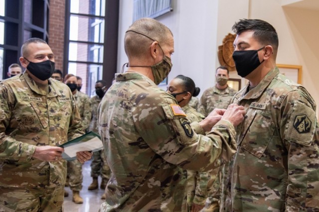 Sgt. Maj. of the Army Michael Grinston (center) assists with the promotion of Sgt. 1st Class Julio De La Cruz Feb. 9, 2021, in the foyer of the U.S. Army Military Police School command section. Grinston visited Fort Leonard Wood to engage with leaders and Soldiers.