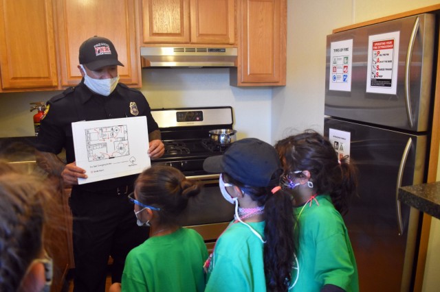 Fire Prevention Officer Alika Publico with the Presidio of Monterey Fire Department shows children how to make a fire exit plan in the department’s Fire Safety and Prevention Trailer during the Monterey Cub Scout Camp at the Presidio of Monterey, Calif., July 29.