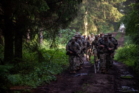 Soldiers from 3rd Battalion, 161st Infantry Regiment conduct a ruck march at Bemowo Piskie Training Area, Poland, July 16, 2021. The dog in the front, Chico, is the unofficial mascot of BPTA, accompanying the troops as they departed the cantonment area. 