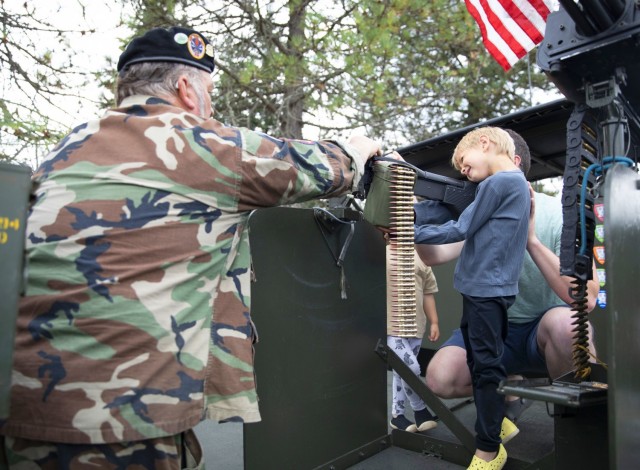 Steve Sumaral, a member of the Gamewarden of Vietnam Past to Present shows attendees the twin M2HB .50 caliber (12.7 mm) machine guns onboard a Navy Patrol Boat, River (PBR)  that was used during the Vietnam War. Sumaral is wearing a black beret, worn only by U.S. Navy's brown-water force, a force that patrolled the Mekong River Delta to transport people to medical facilities, check legal papers and to stop the flow of guns and personnel.