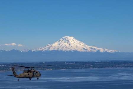 An Army UH-60 helicopter flies to Whidbey Island, Wash. with a view of Mount Rainier for a Soldier reenlistment ceremony, June 17, 2021. 