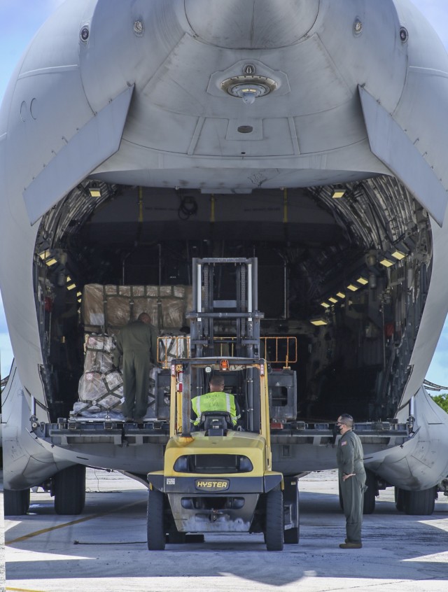 A C-17 Globemaster aircrew assists a member of the Kwajalein airfield team in a cargo loading operation Aug. 14, 2021 at Bucholz Army Airfield on U.S. Army Garrison-Kwajalein Atoll.