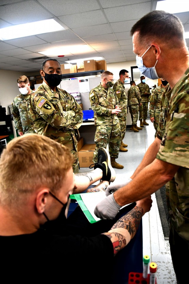 Maj. Gen. Jonathan Woodson, commanding general, Army Reserve Medical Command, observes a blood draw while touring the Soldier Readiness Processing site for the 2021 Cadet Summer Training on Monday, July 12. The SRP site is a part of the ARMEDCOM medical support offered annually to the Fort Knox, Ky. training exercise, and ensures cadets are medically safe to train in the exercise and ready for commissioning. CST is the largest annual training exercise executed by the U.S. Army, graduating almost 10,000 Cadets from Advanced Camp or Basic Camp each summer. More than 250 ARMEDCOM Soldiers have provided support to the exercise, including medics, physicians, x-ray technicians, pharmacy technicians and lab technicians.