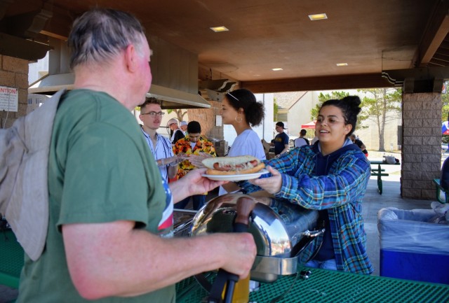 Kirsteen Gomez hands a Presidio of Monterey Family and Morale, Welfare and Recreation customer a bratwurst with sauerkraut during the Volksmarch at the Presidio of Monterey, Calif., Aug. 28.