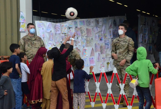 Soldiers supporting the OAR efforts at Rhine Ordnance Barracks often help the transiting children pass time by throwing or kicking balls, playing games or helping them color some of the many artworks on display in the background. (Photo Credit: Shaylee Rawls Borcsani)