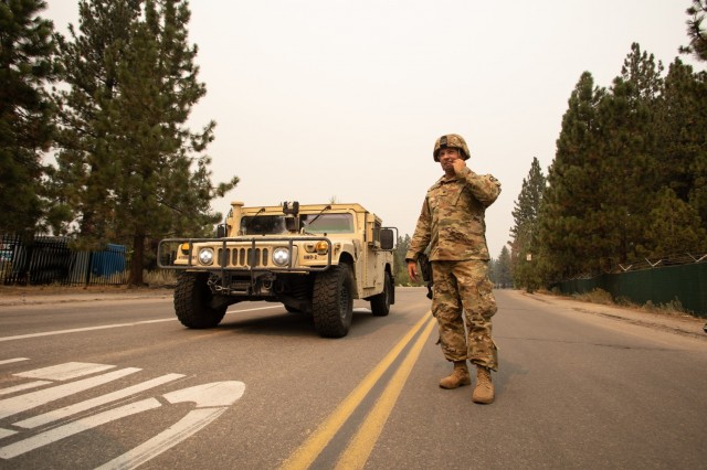 U.S. Army Spc. Dace Taylor, from the California Army National Guard’s 270th Military Police Company, talks to another Soldier Sept. 1, 2021, in South Lake Tahoe, California, as the Caldor Fire encroaches on the evacuated city. Cal Guard activated 150 military police Aug. 30 to support the California Highway Patrol with checkpoints at hard closures while the area was evacuated. (U.S. Air National Guard photo by Staff Sgt. Crystal Housman)