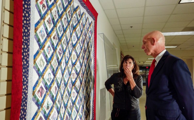 Franklin Childress, director of Army Reserve communications, and Diane Murtha, a former Marine Corps spouse, look at the photos of 9/11 victims printed across a remembrance quilt on display at the Pentagon Quilts memorial, Washington D.C., Aug. 20, 2021.