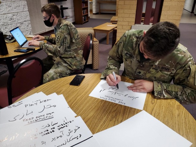 U.S. Army Cpl. Sean Jackett, left, and Spc. Zackary Jensen, Wisconsin Army National Guard linguists, create signs in Dari and Pashto, Aug. 25 2021, to place in a welcome area for Afghan personnel arriving at Volk Field Combat Readiness Training Center near Camp Douglas, Wisconsin. (Photo by Maj. Brian Faltinson)