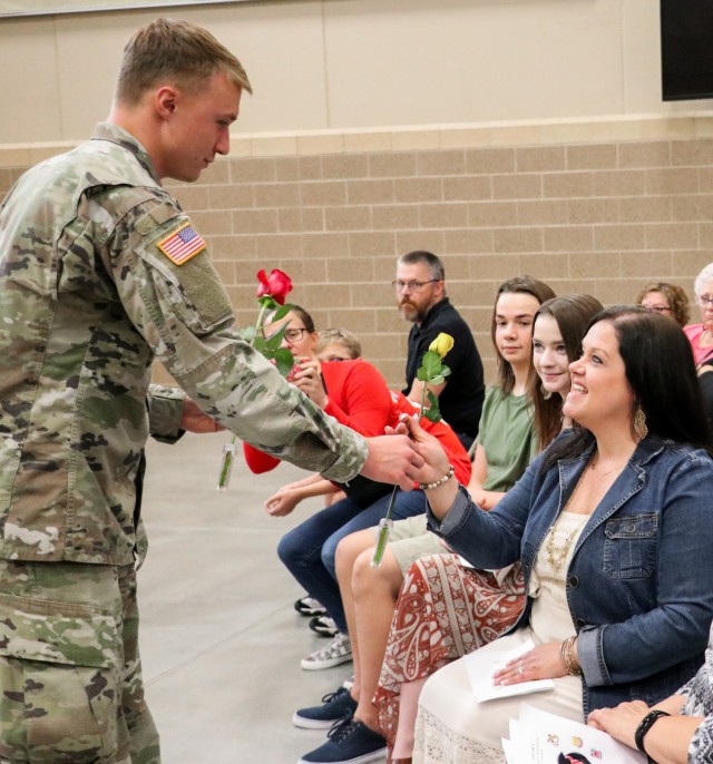 Spc. Tyler Strasser, a cavalry scout with 1st Squadron, 113th Cavalry Regiment, Iowa Army National Guard, presents a rose to his aunt, Kayla Strasser, during the change of responsibility ceremony for the 2nd Infantry Brigade Combat Team, 34th Infantry Division, at the Camp Dodge Joint Maneuver Training Center on Sept. 10, 2021. A yellow rose given to the wife of the incoming command sergeant major symbolizes a new beginning. The ceremony was a unique event, as the colors that represent the lineage and honors of the 2/34th IBCT were passed between two brothers who have dedicated a combined 47 years of service to the Red Bull brigade. (U.S. Army National Guard photo by Staff Sgt. Tawny Schmit)