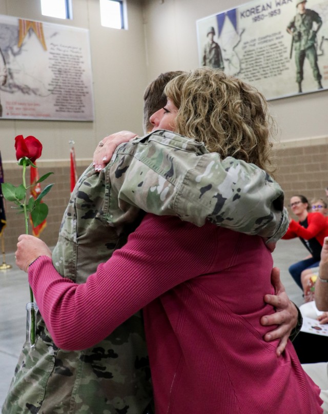 Spc. Tyler Strasser, a cavalry scout with 1st Squadron, 113th Cavalry Regiment, Iowa Army National Guard, presents a rose to his mother, Jessica Strasser, during the change of responsibility ceremony for the 2nd Infantry Brigade Combat Team, 34th Infantry Division, at the Camp Dodge Joint Maneuver Training Center on Sept. 10, 2021. A red rose given to the wife of the outgoing command sergeant major symbolizes gratitude and appreciation for her support to her husband and the unit. The ceremony was a unique event, as the colors that represent the lineage and honors of the 2/34th IBCT were passed between two brothers who have dedicated a combined 47 years of service to the Red Bull brigade. (U.S. Army National Guard photo by Staff Sgt. Tawny Schmit)