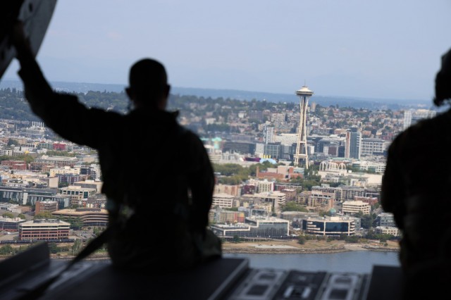 A member of the Royal Thai Army sits on the ramp of a CH-47 Chinook helicopter as it flies above Seattle, Aug. 25, 2021. The Thai Army aviators were taking part in a three-week aviation exchange with members of the Washington National Guard&#39;s 96th Aviation Troop Command. (U.S. National Guard photo by Jason Kriess)