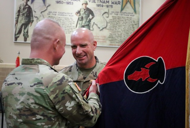 Command Sgt. Maj. Jeremy Strasser, the incoming senior enlisted leader of the 2nd Infantry Brigade Combat Team, 34th Infantry Division, Iowa Army National Guard, receives the unit colors from Col. Derek Adams, the brigade commander, during the during the change of responsibility ceremony for the 2nd Infantry Brigade Combat Team, 34th Infantry Division, at the Camp Dodge Joint Maneuver Training Center on Sept. 10, 2021. The ceremony was a unique event, as Jeremy Strasser assumed responsibility from his brother, Command Sgt. Maj. Matthew Strasser. The two brothers have dedicated a combined 47 years of service to the Red Bull brigade. (U.S. Army National Guard photo by Staff Sgt. Tawny Schmit)