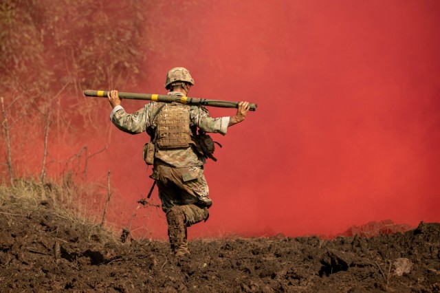 A soldier runs through red smoke with a Bangalore torpedo during Exercise Garuda Shield at Baturaja Training Area, Indonesia, Aug. 12, 2021. Garuda Shield brings together the U.S. and Indonesian armies to train on jungle warfare.