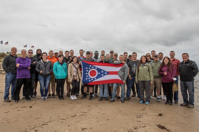 Members of Headquarters and Headquarters Company, 174th Air Defense Artillery Brigade, Ohio National Guard, show the state flag during a visit to Gold Beach in Normandy, France, Aug. 26, 2021. The Soldiers visited the beach as part of a D-Day staff ride.
